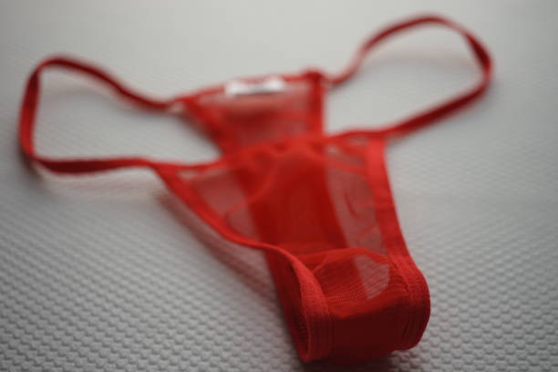 istock Red thong of transparent fine mesh on white fabric with embossed pattern. 1213525872