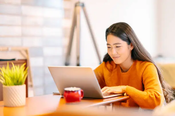 Photo of Young woman using laptop comfortably at home