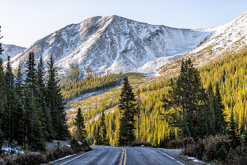 Independence Pass snow rocky mountain view and paved road scenic byway in morning sunrise near Aspen, Colorado in green autumn winter