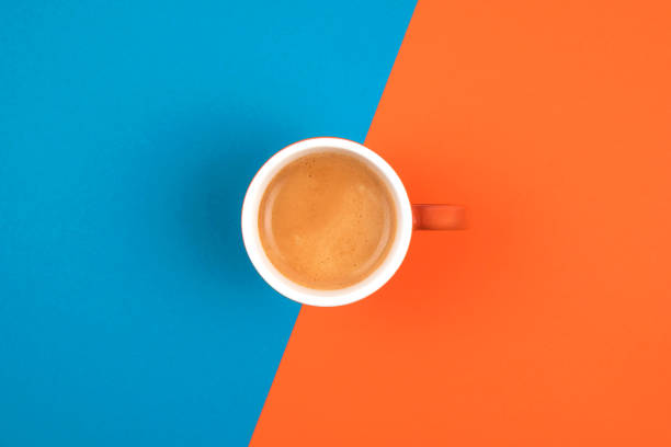istock Fresh brewed coffee in ceramic cup over orange and blue background.  Place for text. 1213531030
