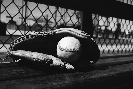 baseball glove with ball on dugout bench in black and white