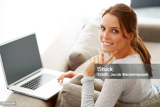 Happy Woman Sitting On Couch With A Laptop Stock Photo - Download Image Now - 20-29 Years, Adult, Adults Only