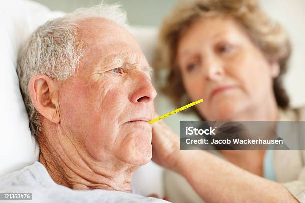 Worried Senior Woman Comforting A Sick Elderly Man Stock Photo - Download Image Now - Fever, Senior Adult, Cold And Flu