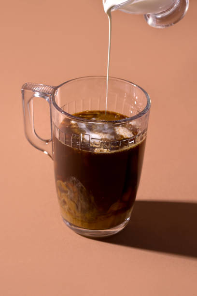 istock black coffee in a cup in which milk or cream is poured on a brown background 1213536044