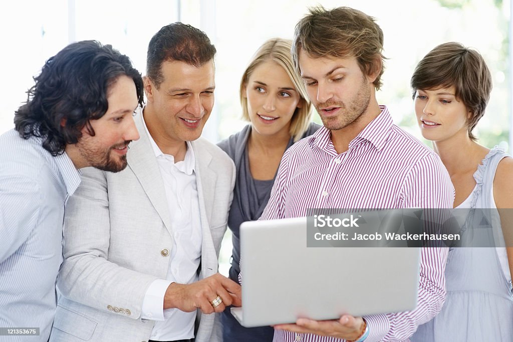 Líder de equipo mostrando sus colegas propuesta en la computadora portátil - Foto de stock de Hombres libre de derechos