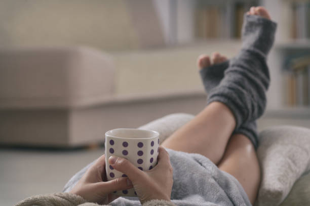 istock Woman with drink lying on sofa 1213537419