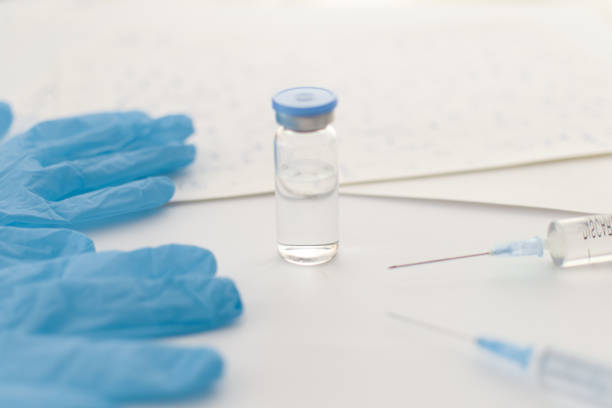 istock Medicine bottle, blue rubber gloves, syringes, papers with handwritten formulas on light background. Coronavirus vaccine development. 2019-nCoV liquid drug, virus antidote. Copy space. Health concept. 1213537626