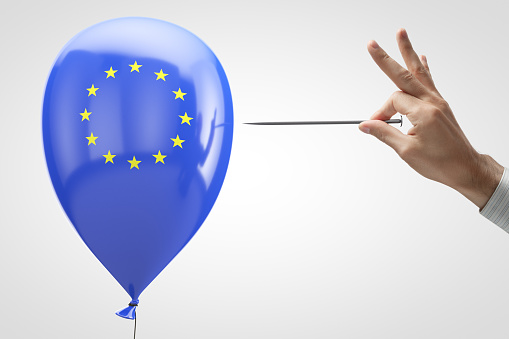 Threat to the European Union. Conceptual photo. Inflatable balloon with the symbol of the European Union and a needle in hand