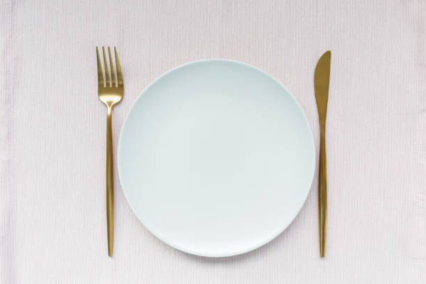 istock Golden cutlery and plate on pink background 1213542997