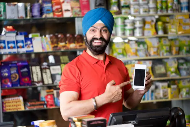 Photo of Happy grocery store owner holding credit card reader