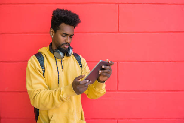 istock Afro man using his digital tablet with earphones. 1213544179