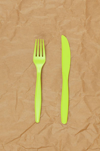 istock Reusable recyclable green fork, knife made from corn starch on brown crumpled craft paper, copy space. Eco, zero waste, alternative to plastic concept. Flat lay. Vertical. Close-up 1213544249