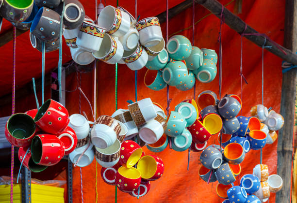 Traditional colorful ceramic cups are hanging and displayed for sale at a handicraft fair.