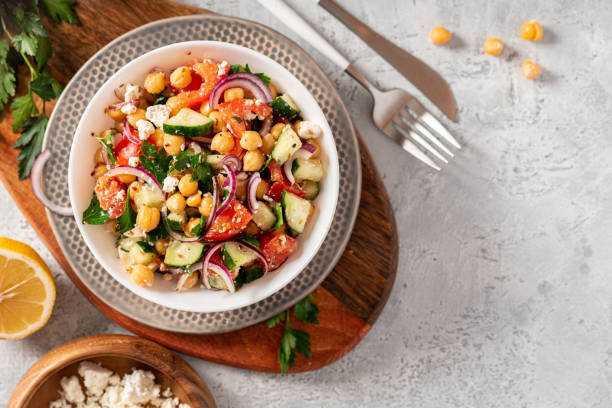 Chickpea salad on a gray background top view Chickpea salad with tomatoes, cucumber, feta cheese, parsley, onions and lemon in a plate on a gray background top view, selective focus. Healthy vegetarian food, oriental and Mediterranean cuisine. mediterranean culture stock pictures, royalty-free photos & images