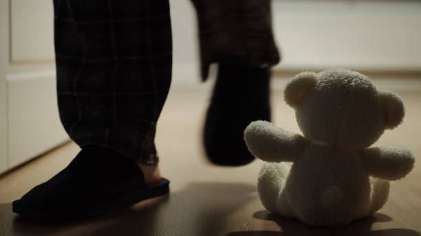 istock Man Passes By A Small Plush Bear Toy Sitting Alone On The Floor 1213546946