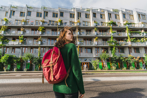 Young Caucasian woman in green sweater with backpack walking in Copenhagen