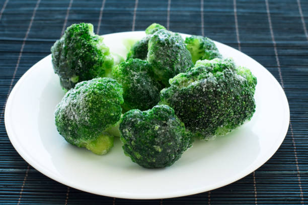istock frozen green broccoli on the white plate and black bamboo wood background 1213551201