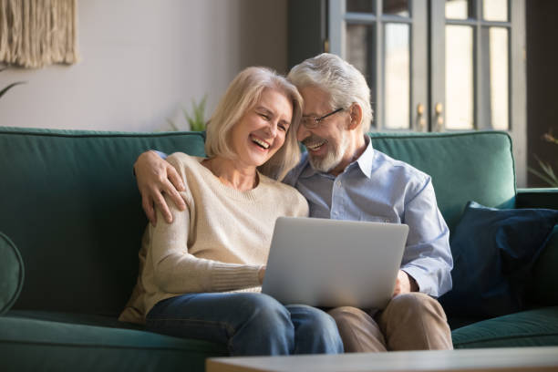 istock Elderly grey-haired spouse laughing and enjoying leisure time with computer. 1213552170