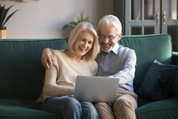 istock Happy smiling grey-haired retirees family spend time together with computer. 1213552171