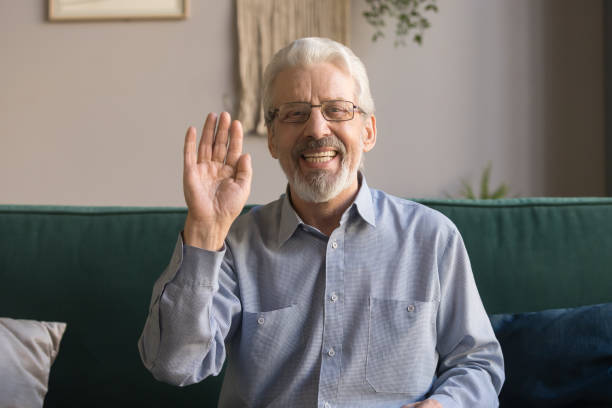 smiling senior man wave at camera talking on video call - senior adult happiness computer looking at camera imagens e fotografias de stock