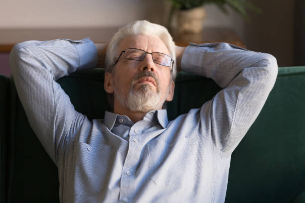 istock Tired elderly man fall asleep on cozy couch at home 1213552221