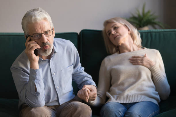 Worried elderly husband call emergency for sick wife Anxious elderly husband hold wife hand call talk with emergency, ask help for woman having heart attack, worried mature male speak with 911 saving sick senior spouse suffering from coronary disease coronary artery photos stock pictures, royalty-free photos & images