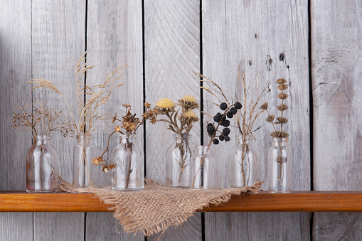 Bouquets of dry grass in glass bottles.