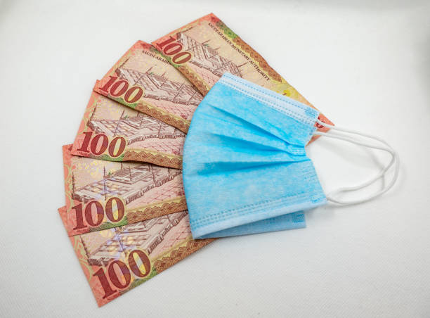 istock Saudi Arabian 100 Riyal bank note with surgical protective face mask 1213555435