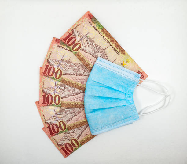 istock Saudi Arabian 100 Riyal bank note with surgical protective face mask 1213555437