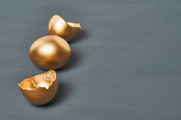istock Golden egg and shells on dark concrete background. Concept of easter, pricelless ideas, successful business investment or luxury breakfast. Copy space 1213555577