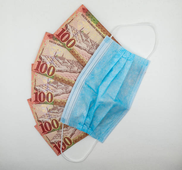 istock Saudi Arabian 100 Riyal bank note with surgical protective face mask 1213555642