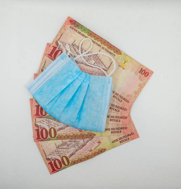 istock Saudi Arabian 100 Riyal bank note with surgical protective face mask 1213555790