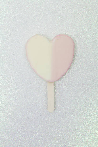 вкусное и освежающее эскимо в форме сердца; двойная вкусовая палитра. - flavored ice lollipop candy affectionate стоковые фото и изображения