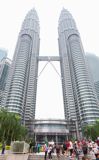 Kuala Lumpur, Malaysia - November 25, 2019: Tourists take photos near Petronas Twin Towers, vertical street view