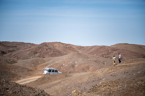 Africa, Djibouti, Lake Abbe. On the pathway leading to lake Abbe a four wheel drive car is parked. two persons are walking down a hill