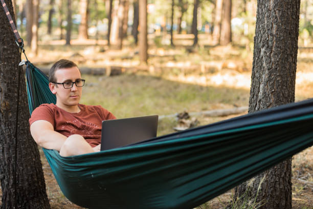 istock Man working on laptop in hammock in forest 1213557258
