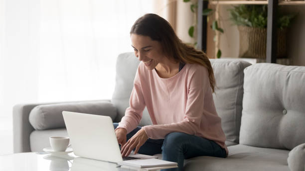 istock Happy young woman laughing using laptop sitting on sofa 1213557396