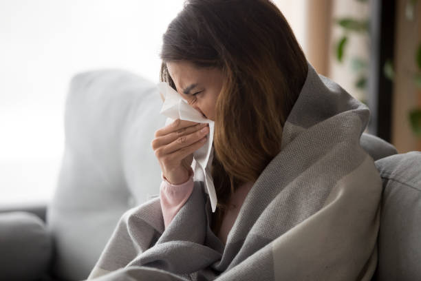istock Ill young woman covered with blanket blowing nose got flu 1213557408