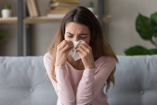 istock Allergic ill woman holding tissue blowing running nose 1213557414