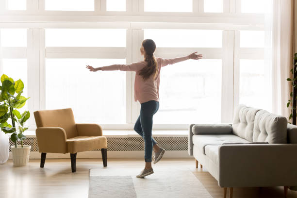 glückliche aktive junge frau tanzt allein im modernen wohnzimmer - joy of living stock-fotos und bilder