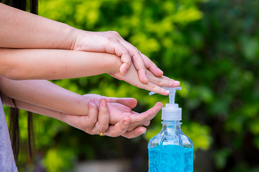 Blur background of mother cleaning her kids hand with alcohol gel sanitizer pump for hygiene protect weak ill chemotherapy, aids, kids patient from flu, germ, bacteria and virus covit-19 infection.