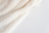 Soft cozy plush fabric with pile lies in beautiful folds on white marble countertop background. Copy space.