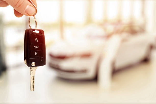 car sales showroom and person holding car key in hands car sales showroom and person holding car key in hands car key photos stock pictures, royalty-free photos & images