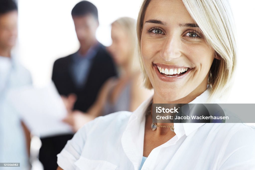 Smiling woman with colleagues discussing in the background  20-29 Years Stock Photo