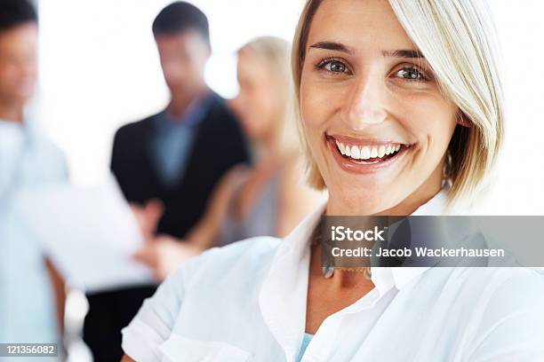 Smiling Woman With Colleagues Discussing In The Background Stock Photo - Download Image Now