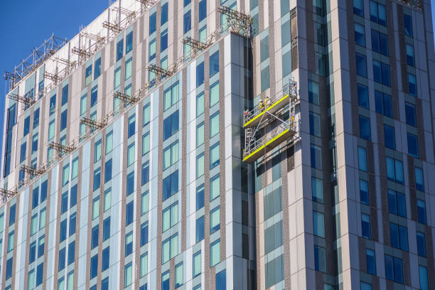 trabalhadores da construção não identificados em andaimes suspensos inspecionando / instalando revestimento em um edifício de alto nível em londres - uk scaffolding construction building activity - fotografias e filmes do acervo