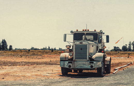 Lodi, California, USA - June 15, 2017: old Peterbilt truck with a gas tank on a background of old rural barns and dry fields in Lodi, California, USA. Traditional american rural landscape