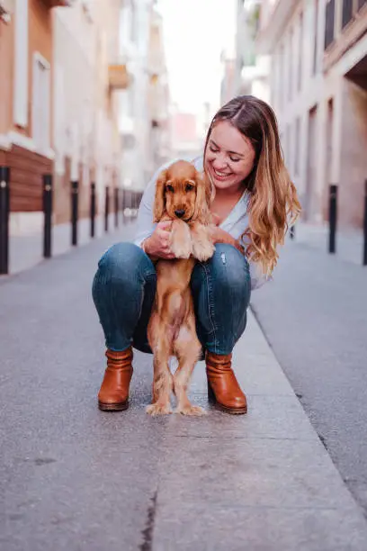 young woman at the street hugging her cute cocker dog. Lifestyle outdoors with pets