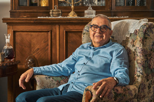 Senior Jew sitting in armchair in traditional home Senior Jew poses sitting in armchair in traditional home against the backdrop of menorah yarmulke photos stock pictures, royalty-free photos & images