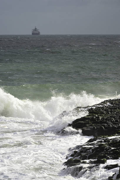 istock Rough waves beating against reefs, and cargo ship off shore 1213570305